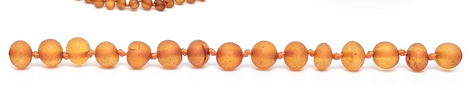 Close view of raw cognac amber bead surfaces and the knots between them